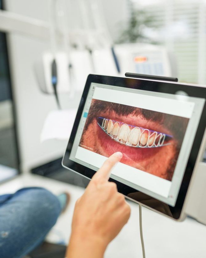Dental professional pointing at a tablet showing a digital smile design of a patient's smile